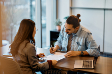 Un jeune homme signe un contrat avec un conseiller bancaire